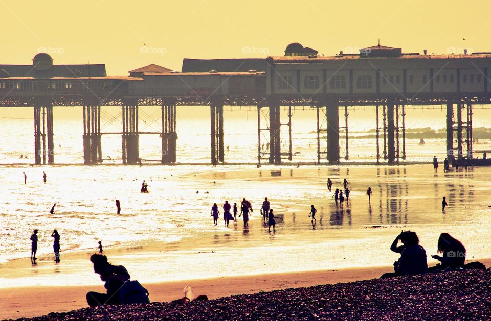 The former Hastings pier dominates this image of people on the beach at sunset