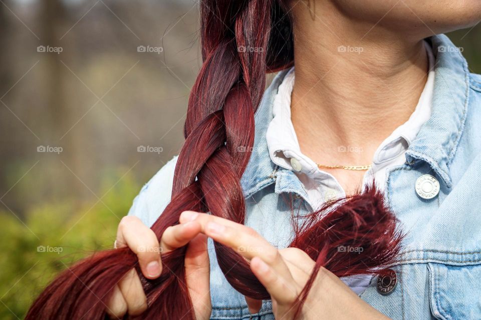 Young woman is braiding her beautiful red long hair