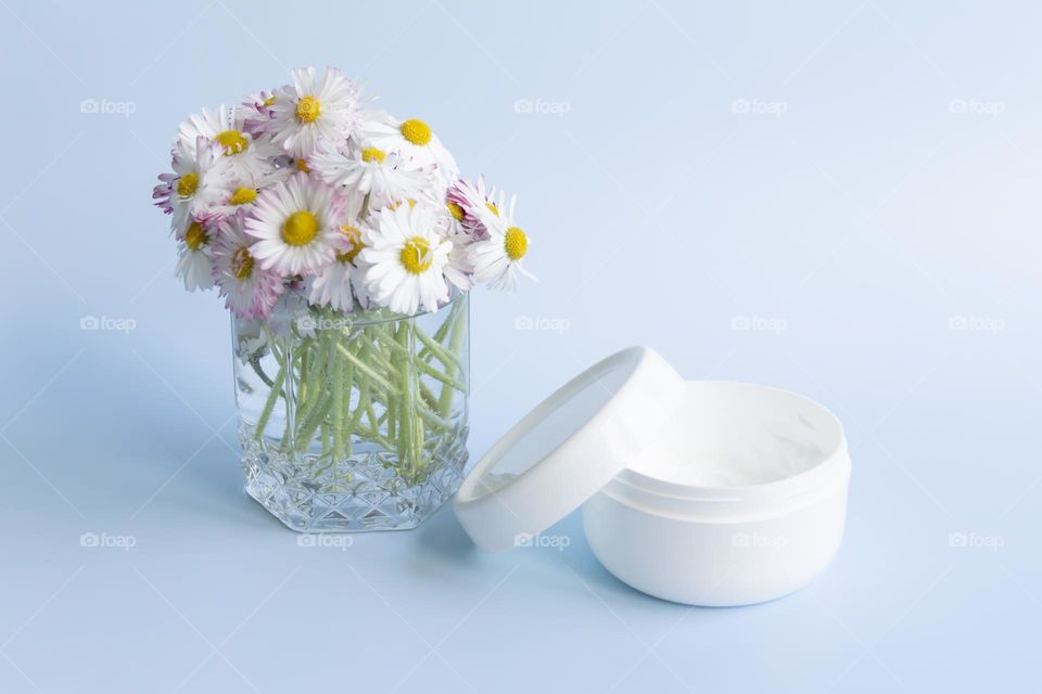 Jars with cosmetic products, beauty cosmetics in a white jar with cream and water with fragrant flowers.