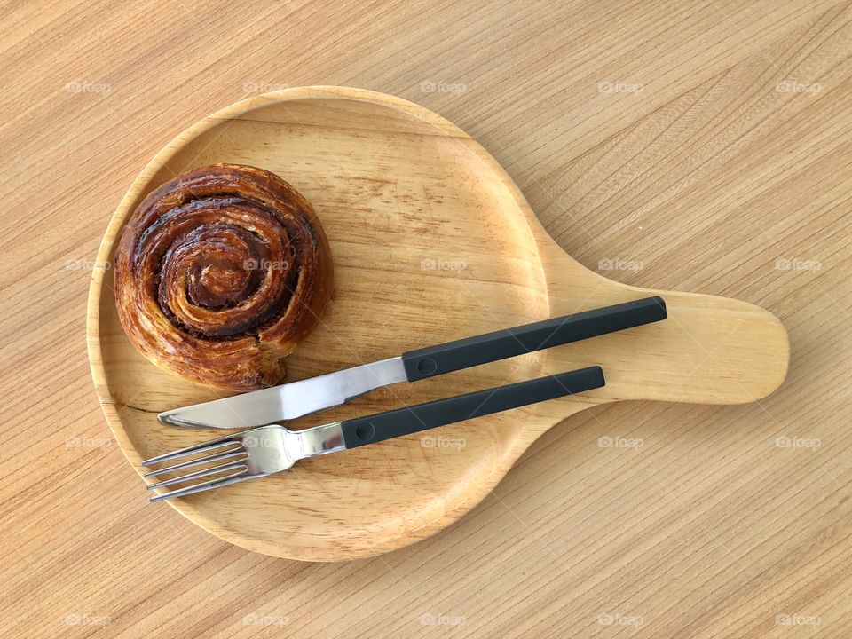 Bakery in wooden plate and knife with fork