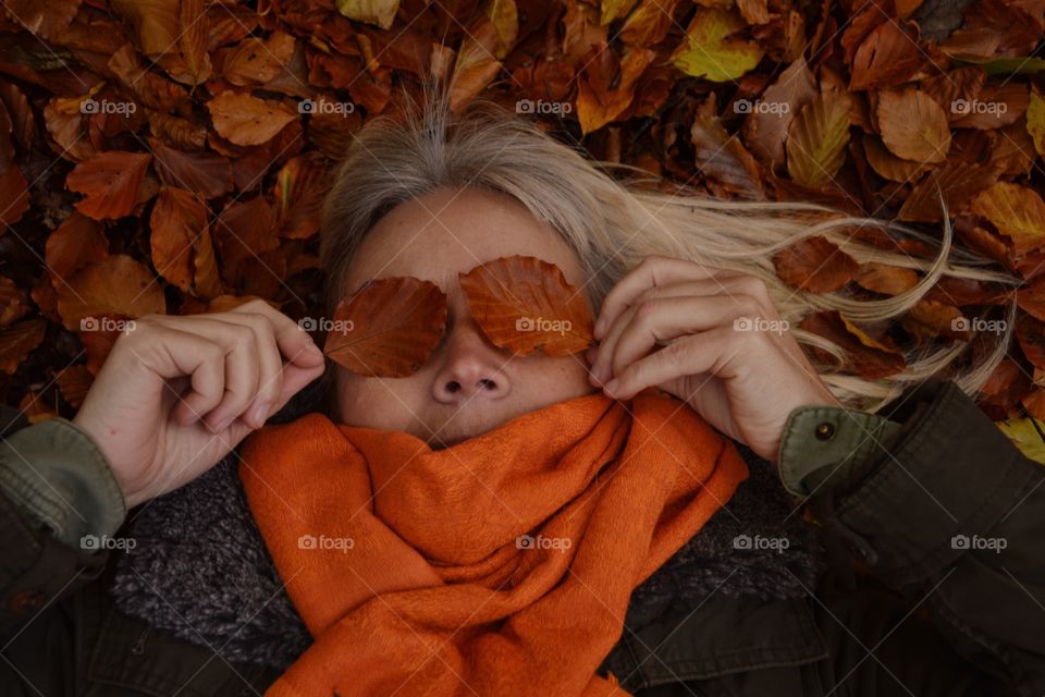 Woman covered her eyes with autumn leaves