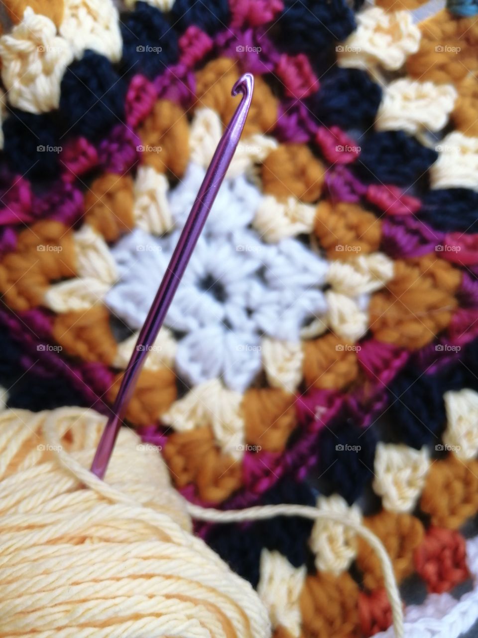 Crocheted Granny Square, a Ball of Yellow Yarn and a Hook, White, Yellow, Orange, Purple, Black,