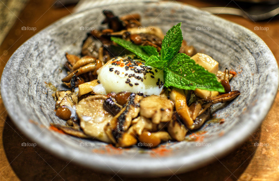 Mushrooms with loe tempered eg and mint on a bowl