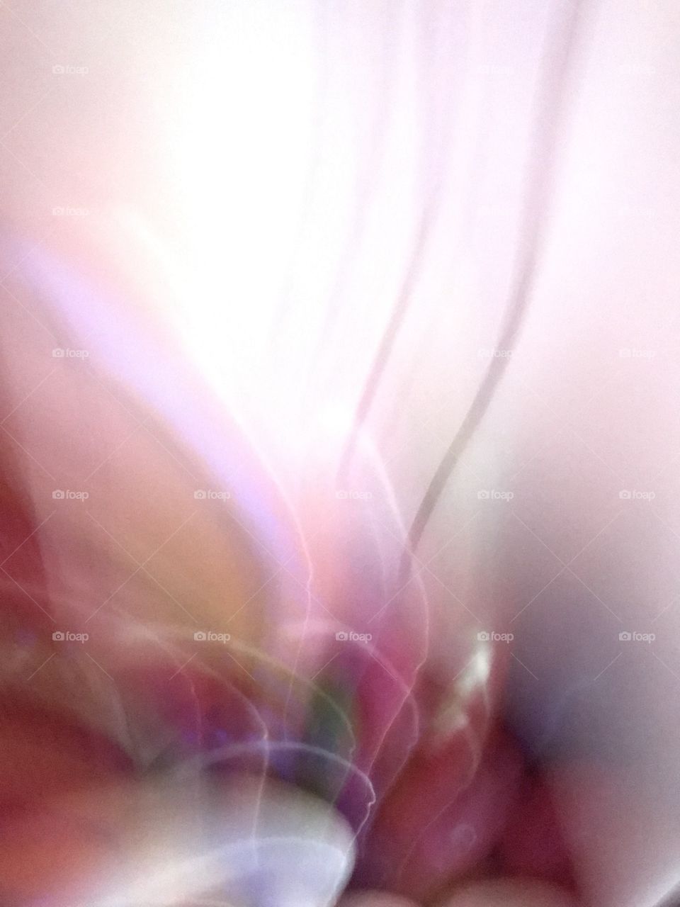 An abstract of rounded beams of darker coloured light emerging from the base of the photo. As it fans out towards the the top of the photo the colours fade and the light intensifies. This was taken while experimenting with shots of jelly beans!