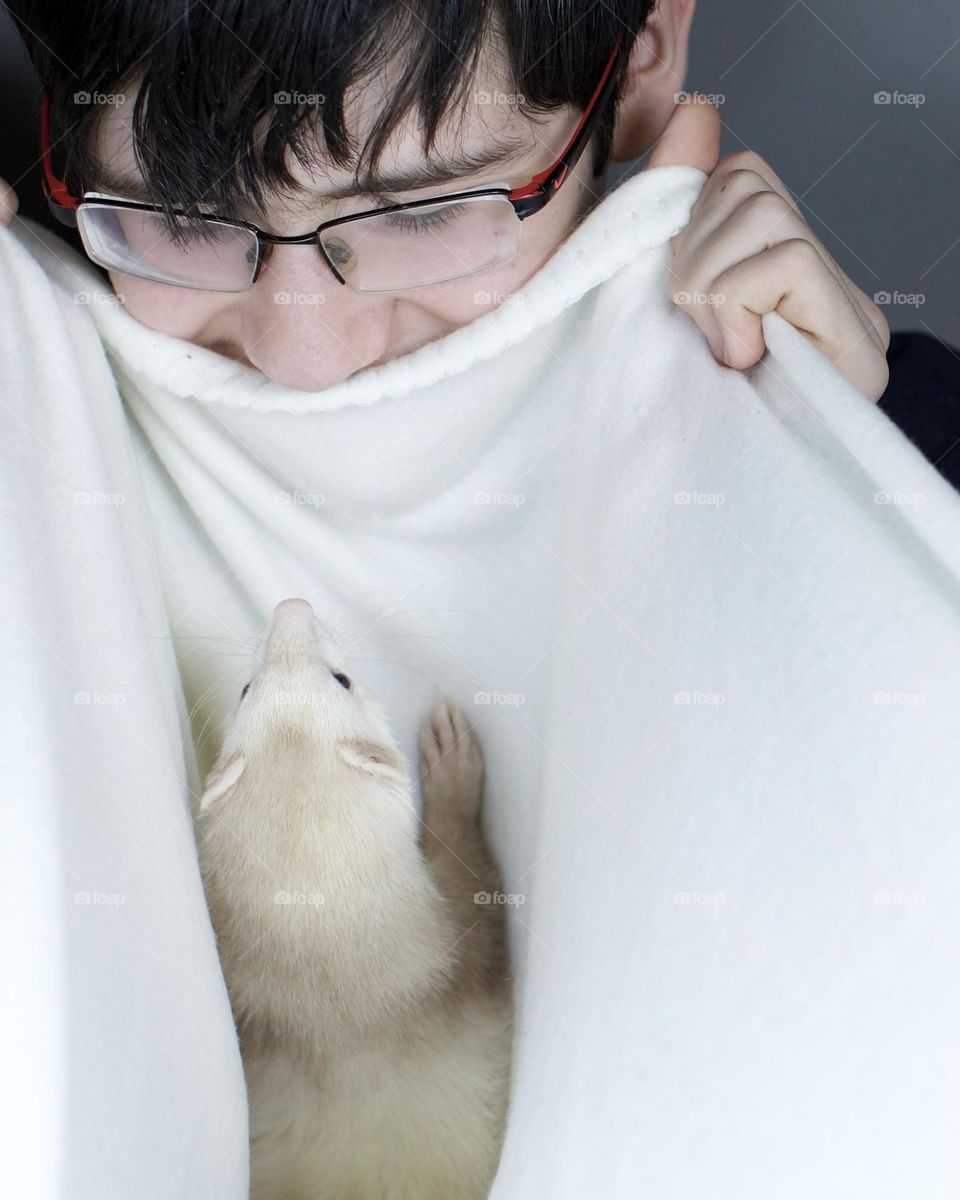 Teen playing peek a boo with his ferret