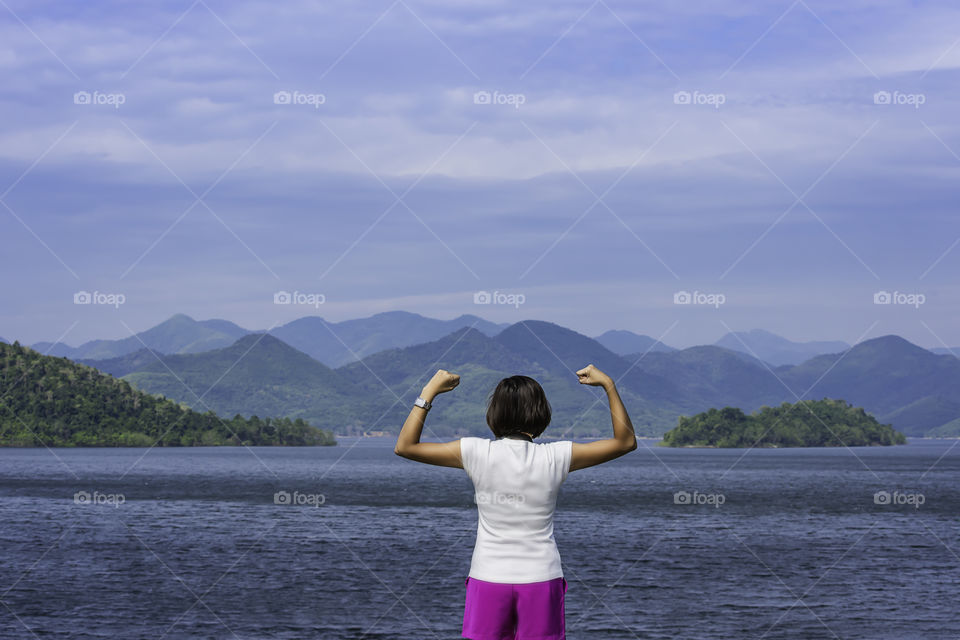 Women raise their arms at Kaeng Krachan Dam phetchaburi in Thailand and the clouds.