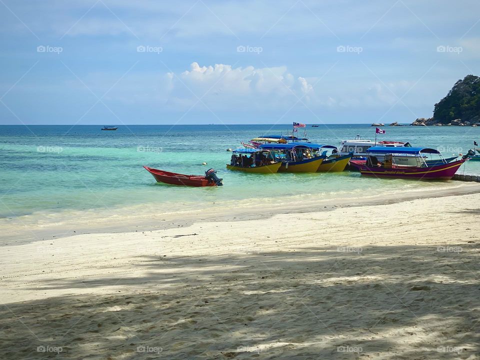 Row of boats on the blue beach on a sunny day.
