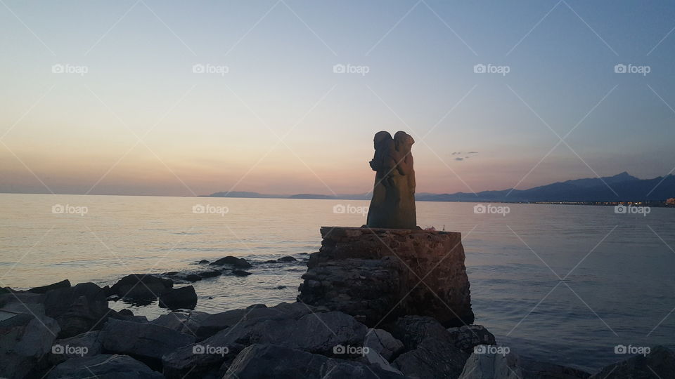The statue standing on the side of the sea by the picture taken in the afternoon