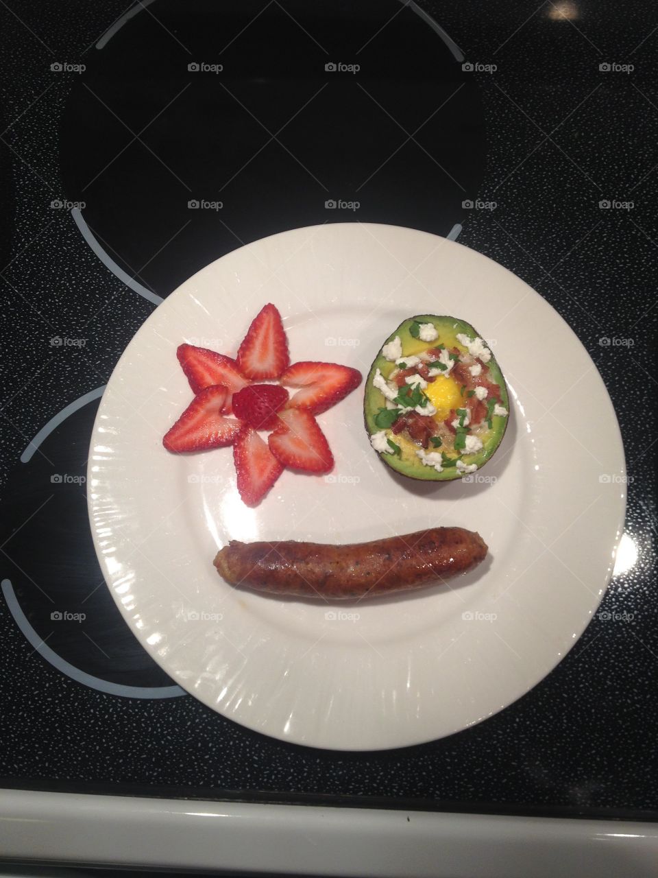 My breakfast has a face! Baked egg in an avocado with sliced strawberries and farm fresh local turkey sausage. 