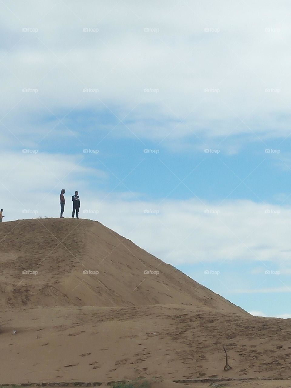 Two people stand on a sand knee.