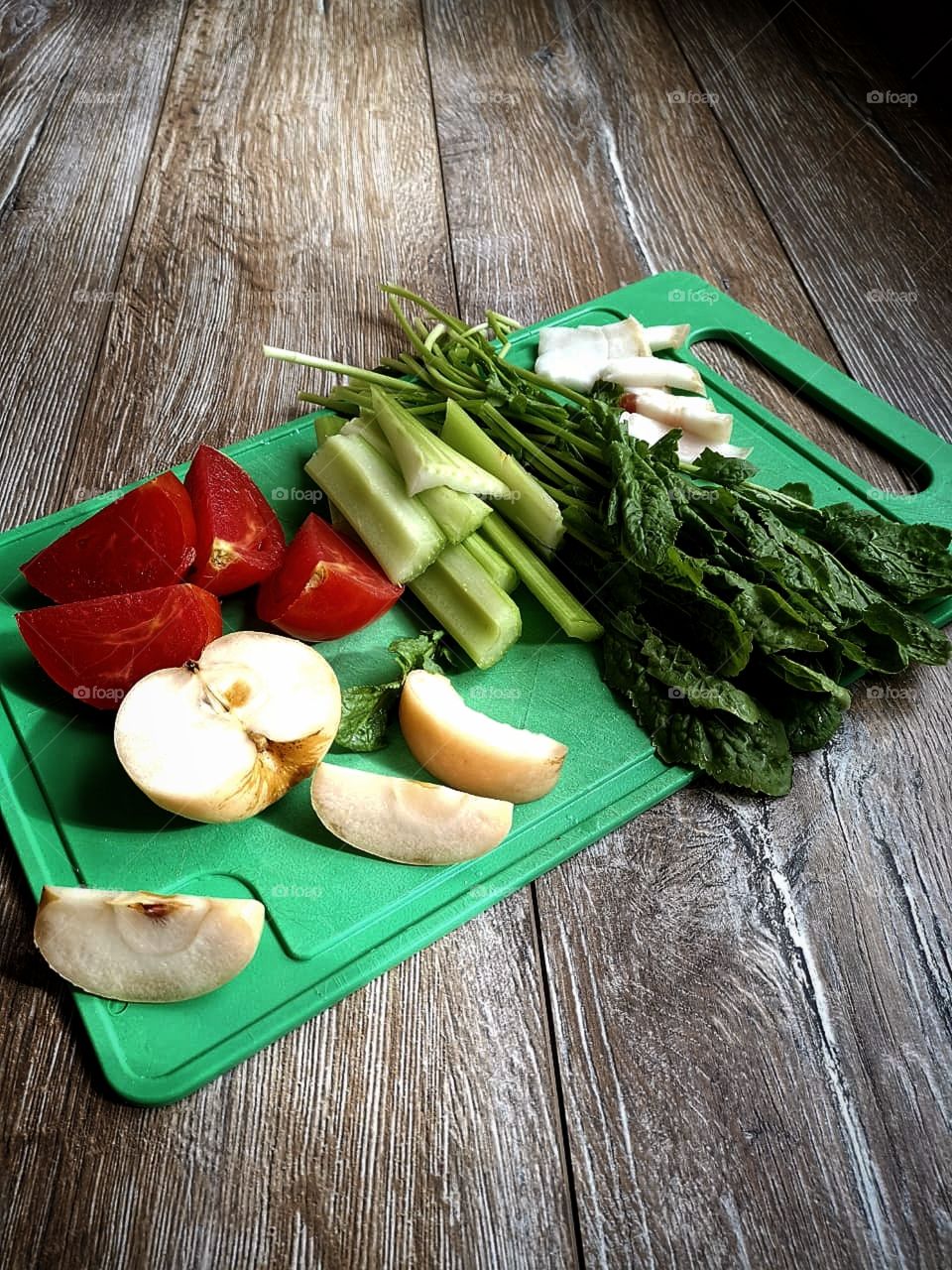 Chopped fruits and vegetables.  Apple, cucumber, tomato, bunch of greens and bacon
