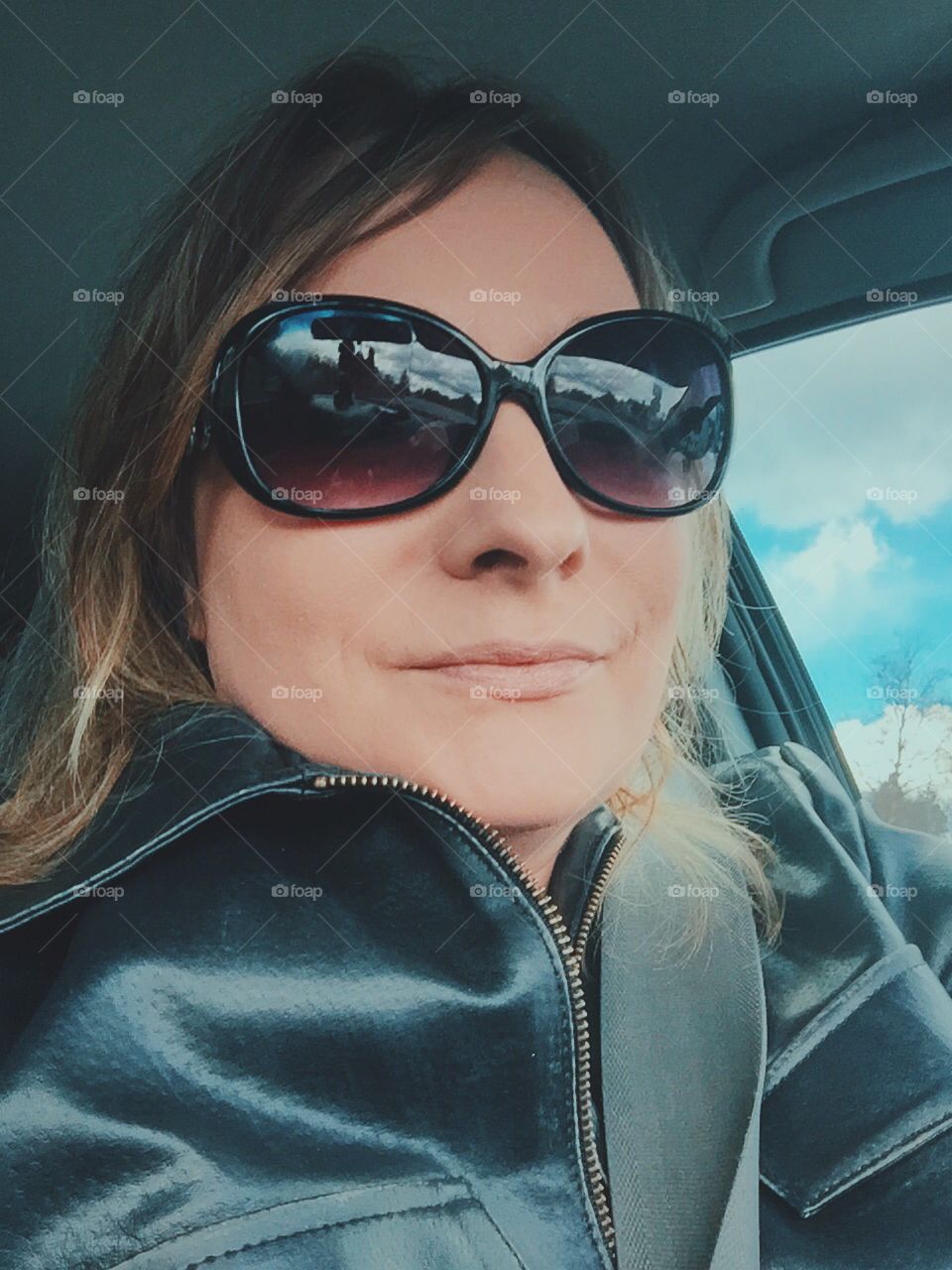 Young woman sitting in car wearing sunglasses