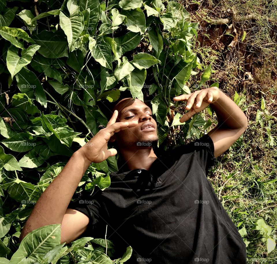 Young man lying on foliage and enjoying nature 