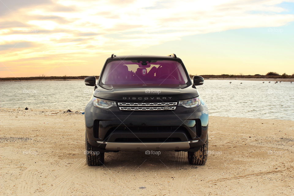 Black 2017 land rover discovery hse offroading at beach on sand at sunset, jetty park, matagorda texas