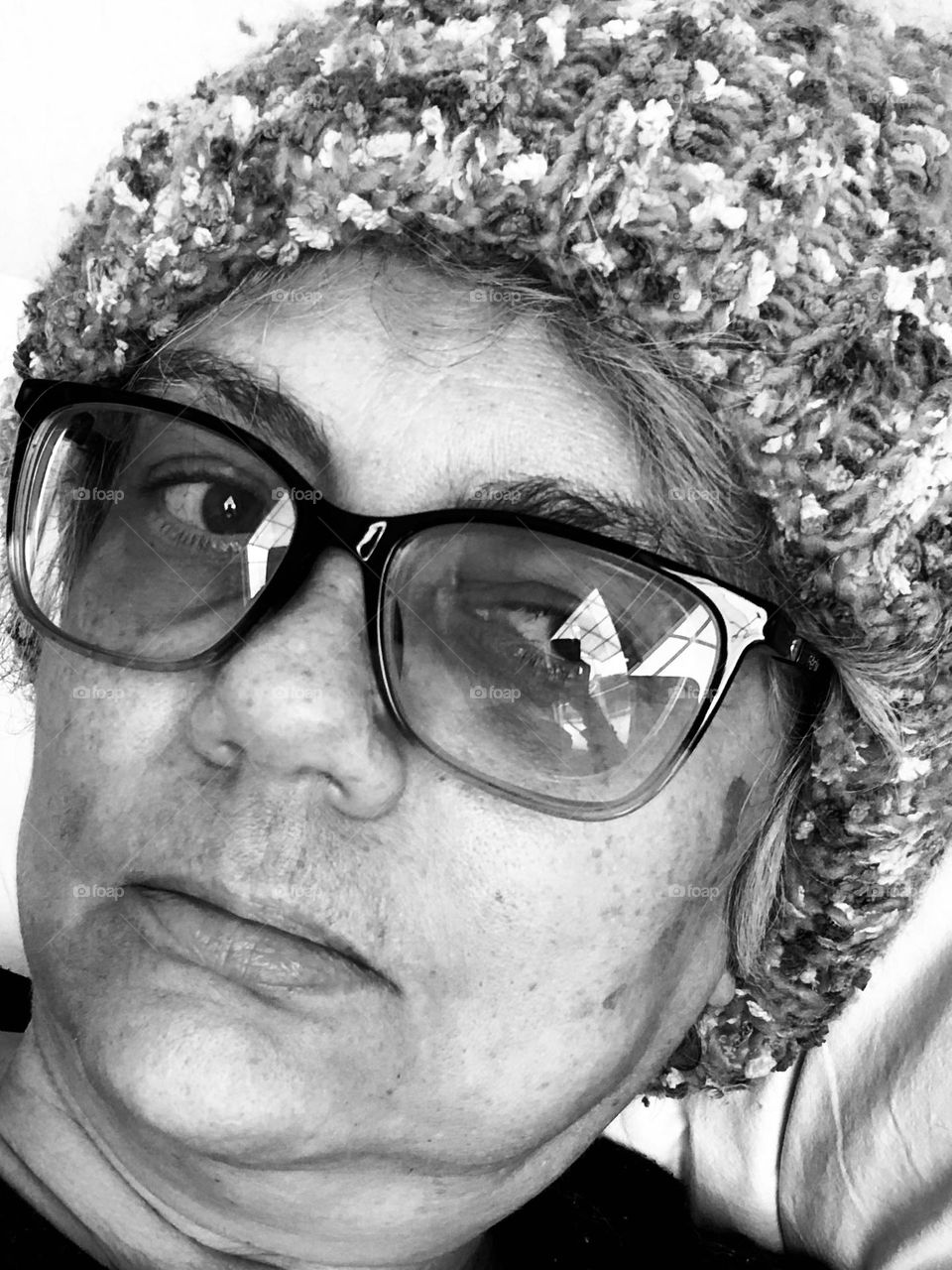 Woman in a wool hat shows her emotions for being stuck indoors during a particular cold winter weekend. 