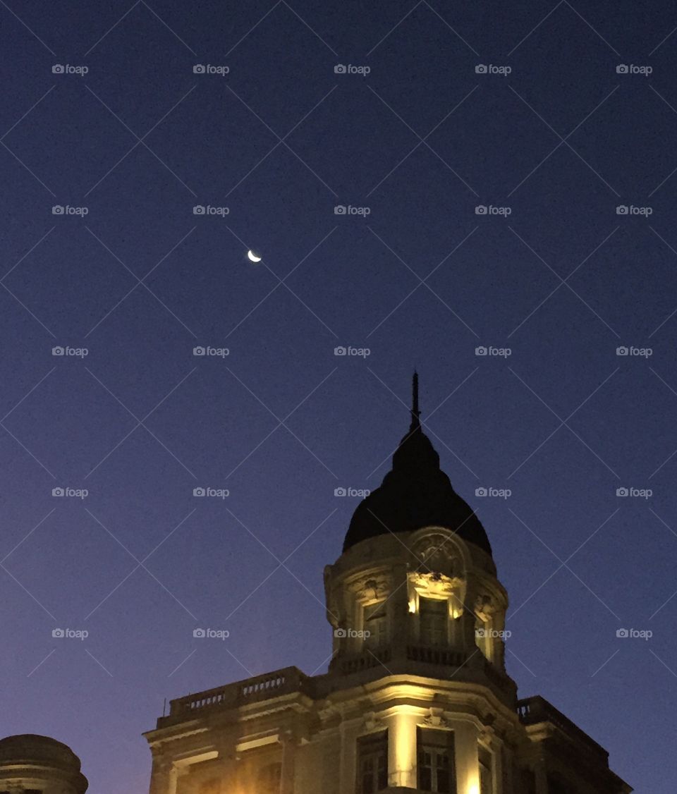 Moon and Architecture. Photo taken at a Uruguayan square, showcasing the moon and a tower with beatiful architecture