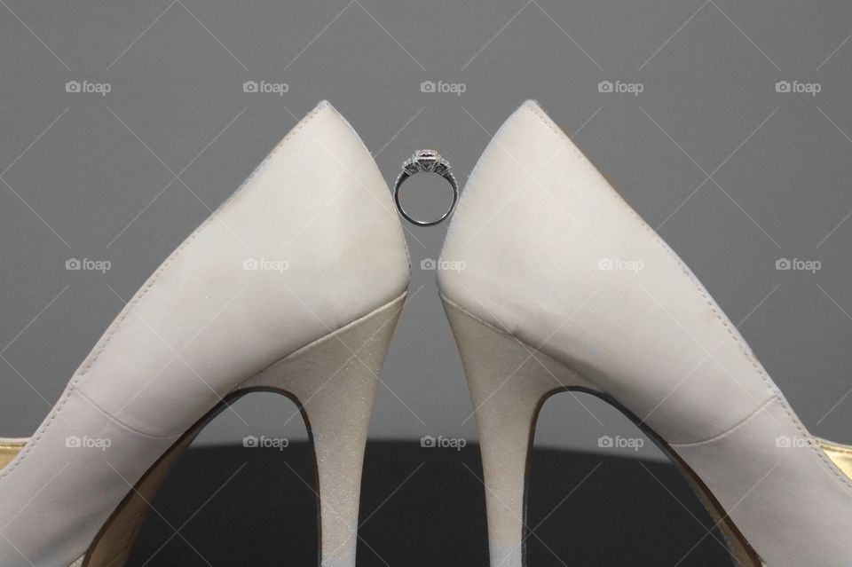 Wedding ring and shoes. Wedding ring suspended between woman's shoes