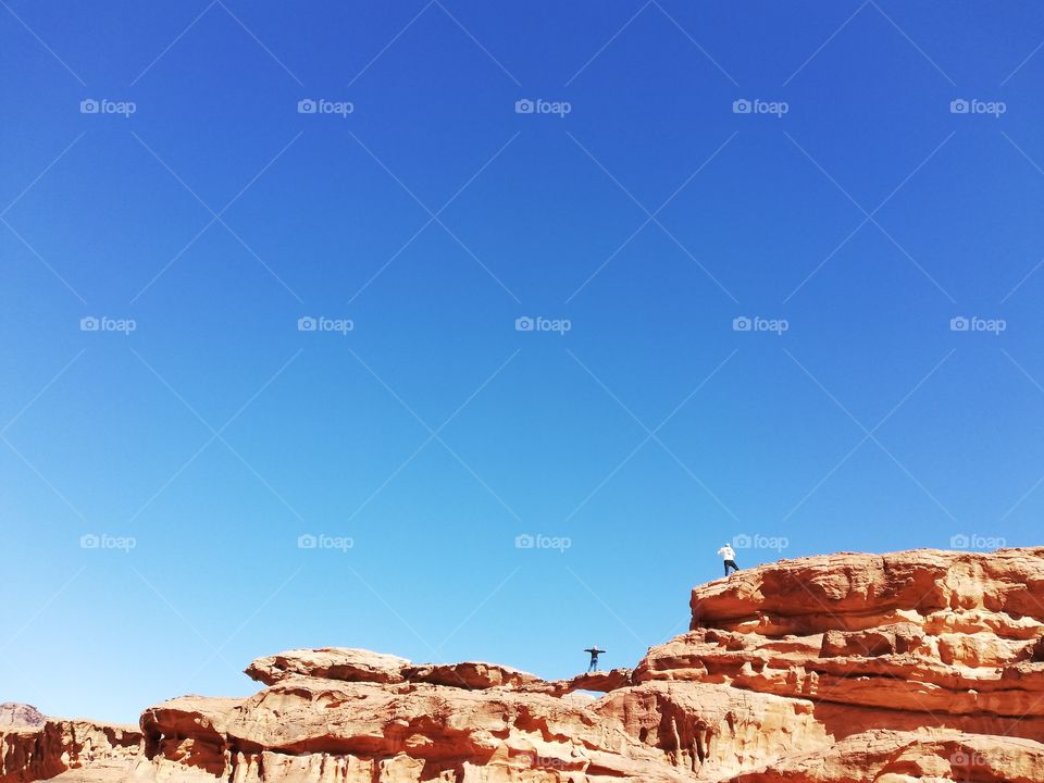 People above a natural arch in Wadi Rum