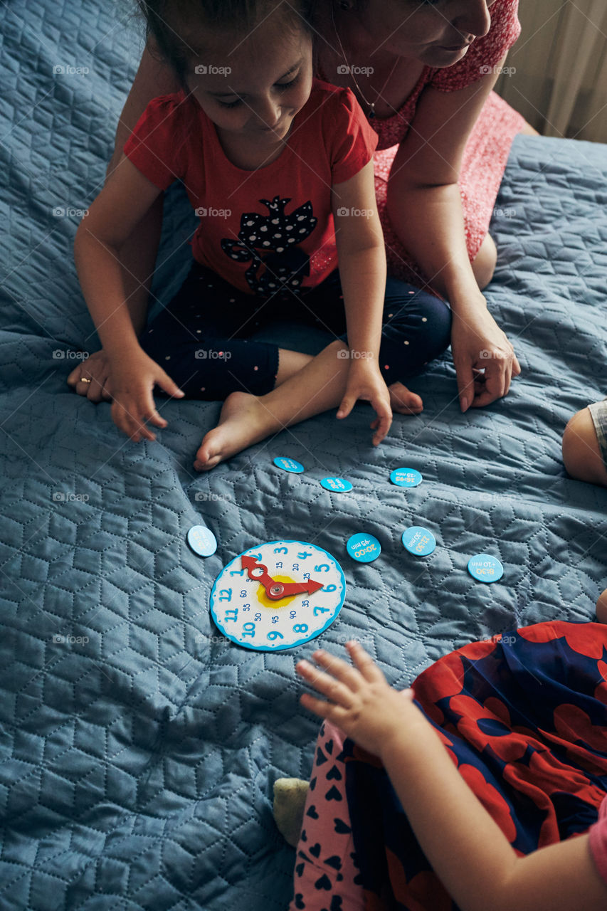 Kids learning how to tell time from clock and set the hands in the correct position. Teaching preschoolers tell time. Candid people, real moments, authentic situations