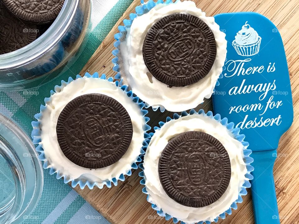 Oreo cookie ice cream cupcakes on a wooden board and white and blue background 