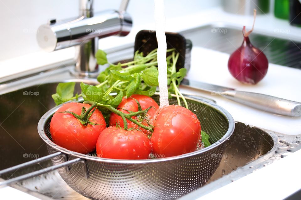 Water falling on tomatoes in colander