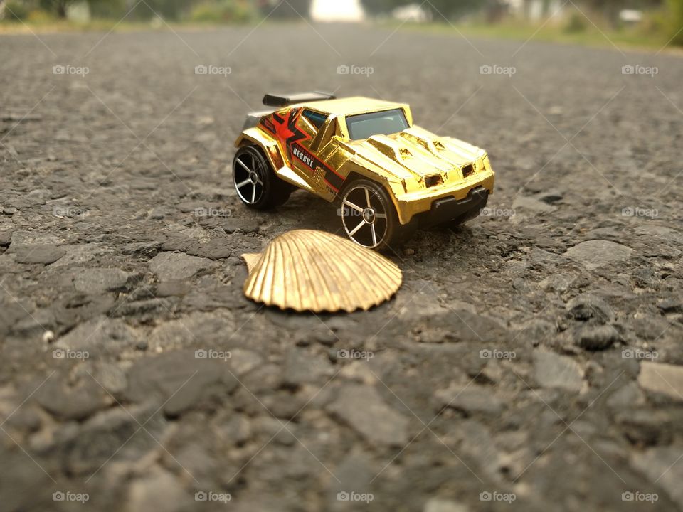 Gold car standing by a gold shell.