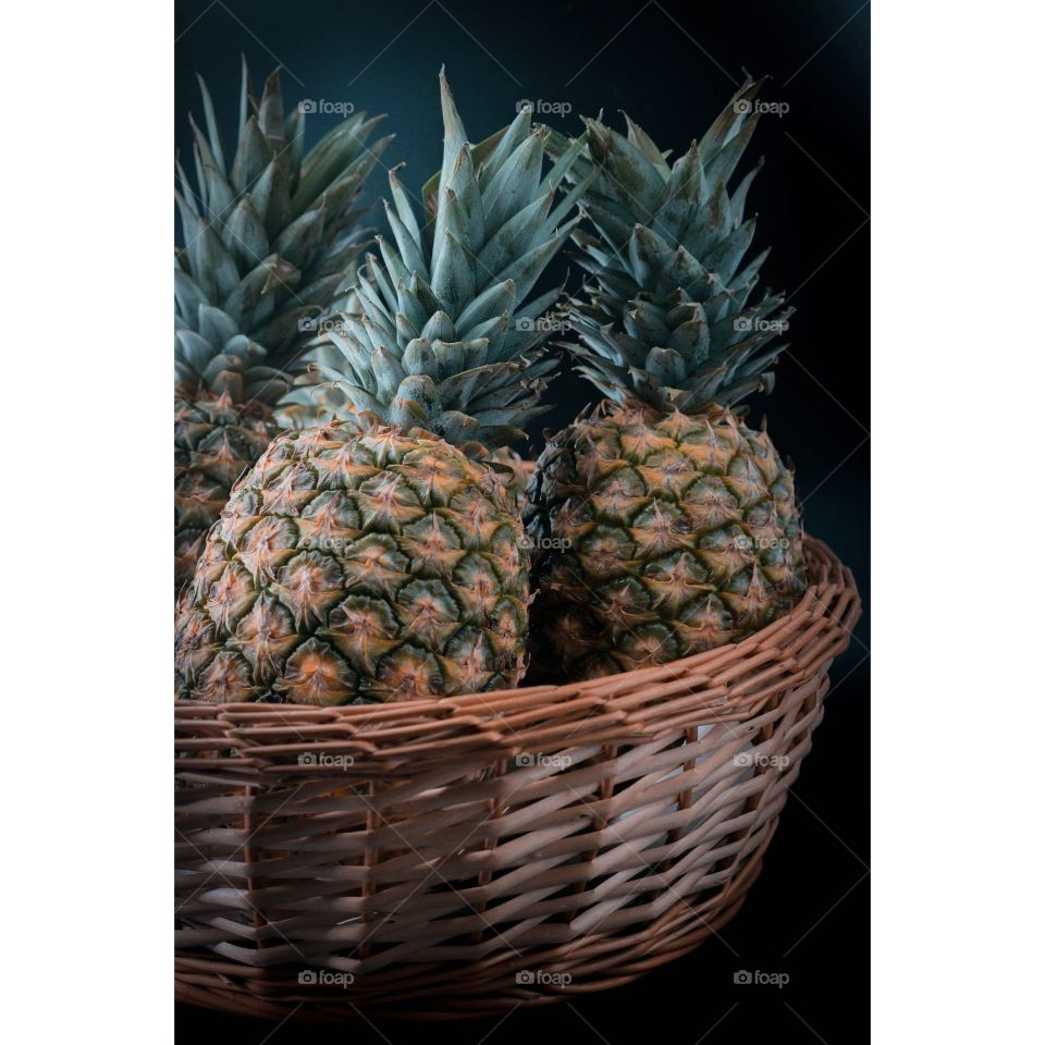 pineapples in a wicker basket on a black background