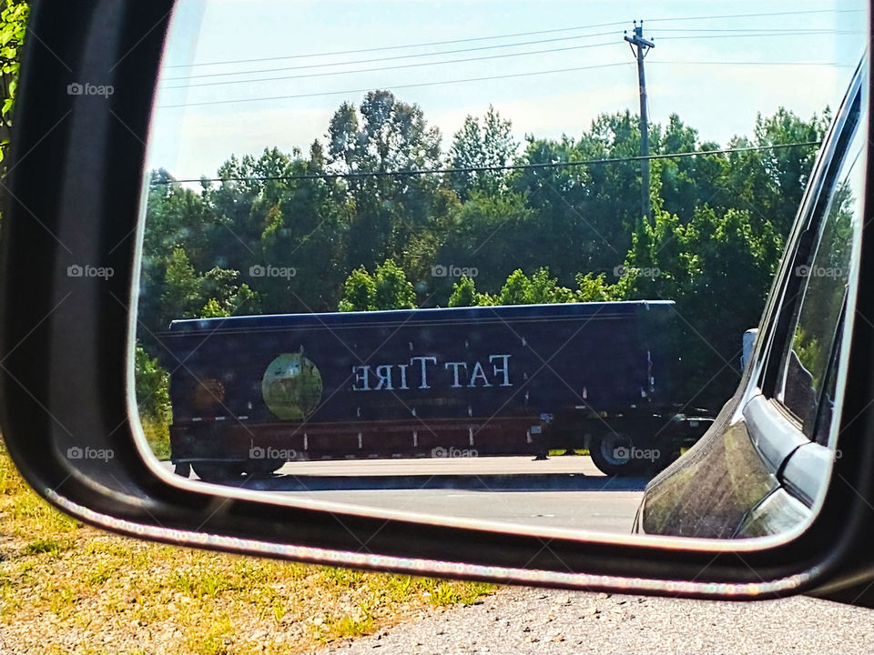Fat Tire Beer Truck drives by and seen in side mirror as Im pulled over with a flat tire.