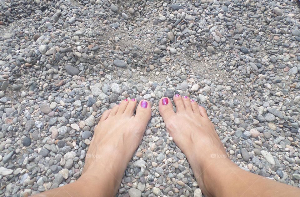 pies uñas pintadas de rosa sobre piedras