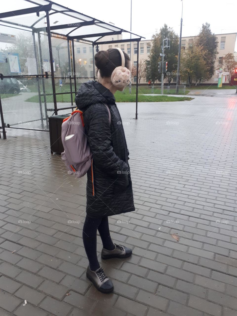 Girl on the way to school, standing at the bus stop and waiting for bus autumn

￼