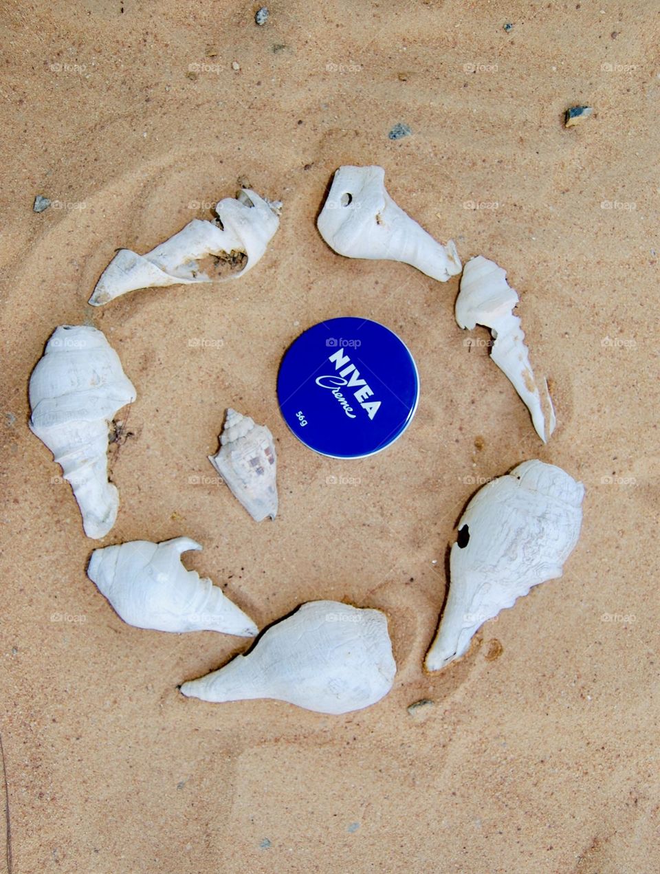 Nivea creme in the sand beach in shells frame 