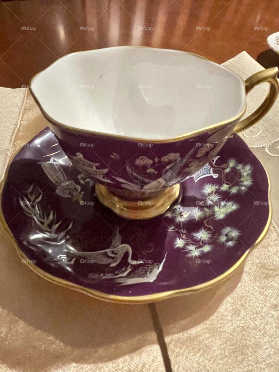 The antique purple tea cup and saucer feature an exquisite traditional Asian design, characterized by intricate hand-painted details. The overall appearance exudes a sense of cultural heritage and refined artistry.