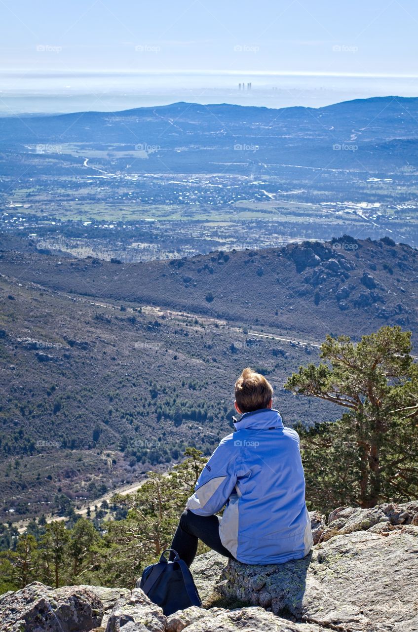 Woman sitting on top of a hill contemplating the view of the city