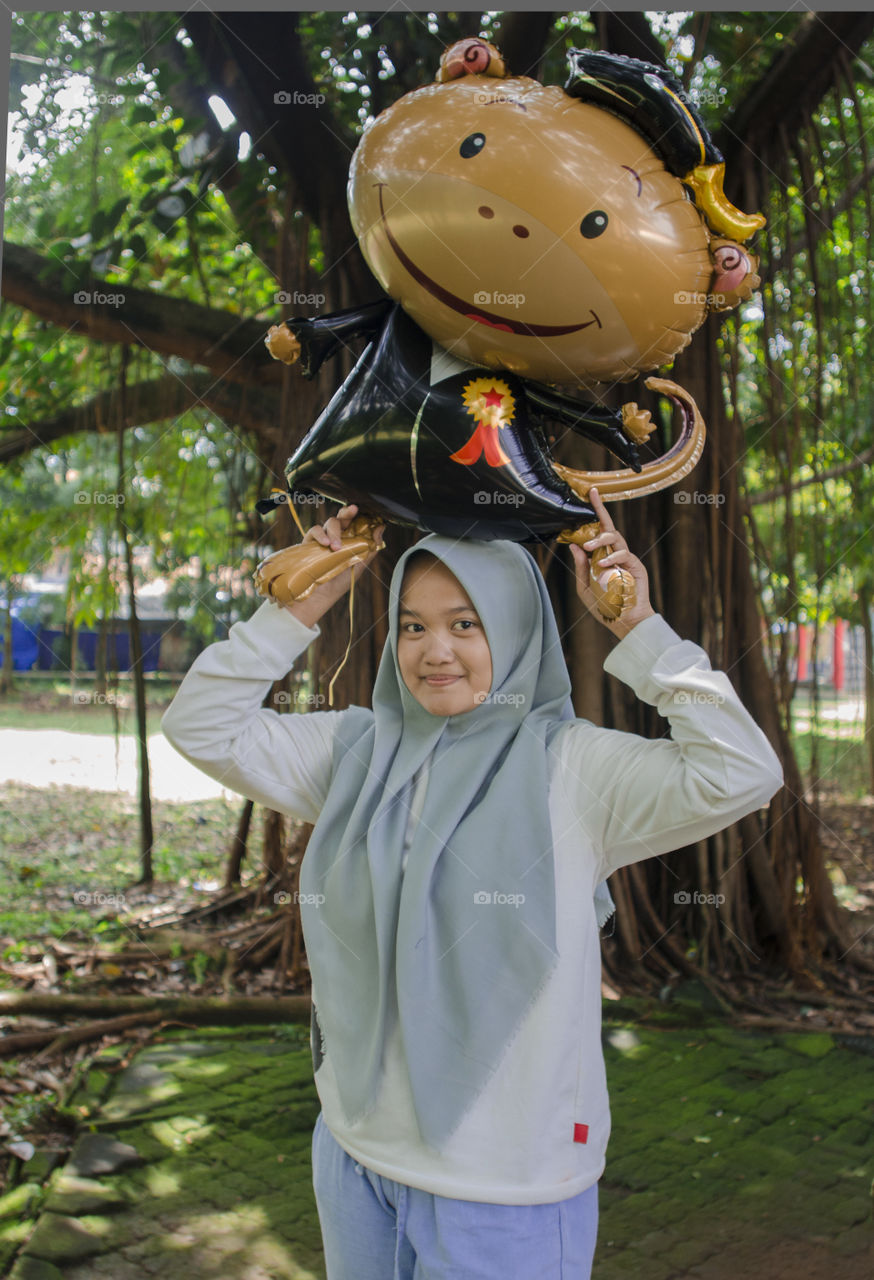 a girl holding a monkey balloon