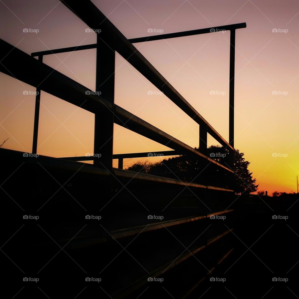 The rails and gate of a cattle pen at sunset form rectangles in the setting sun