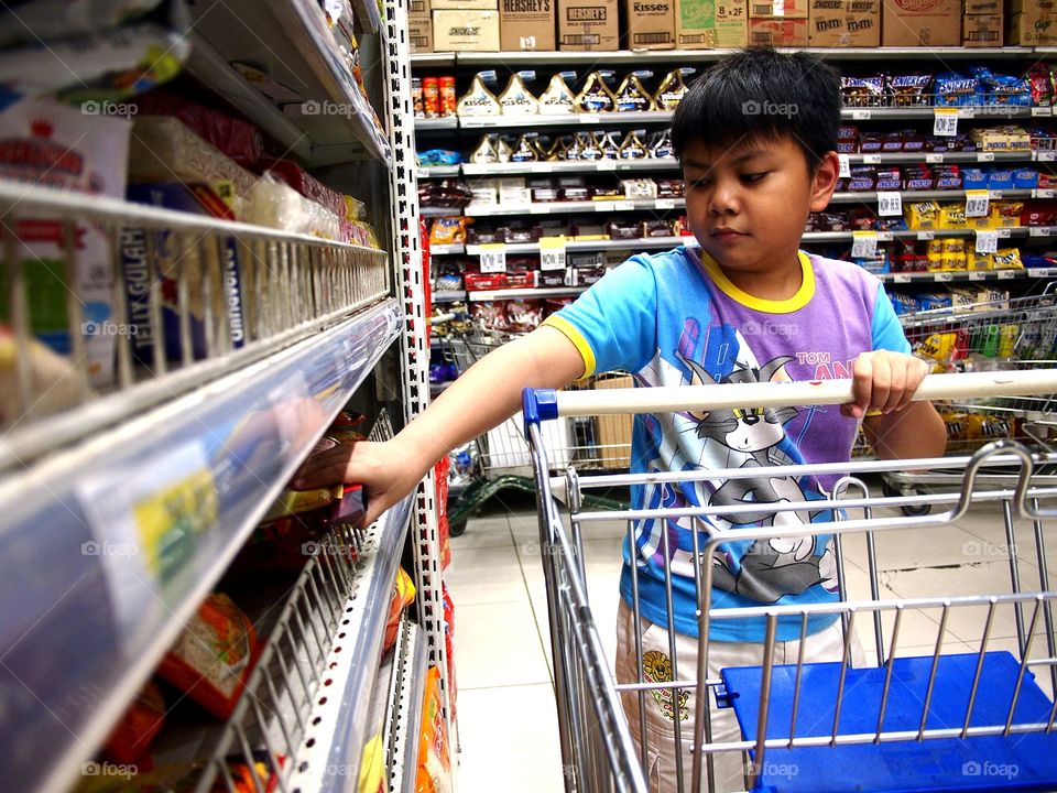 a young boy getting products from a grocery shelf