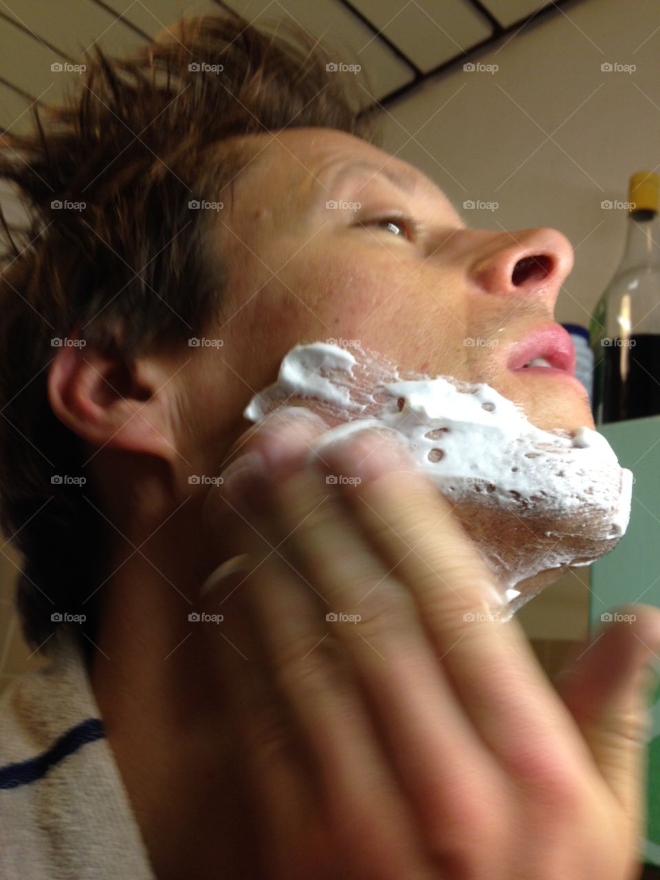 Man applying shaving cream in preparation of his daily shaving routine.