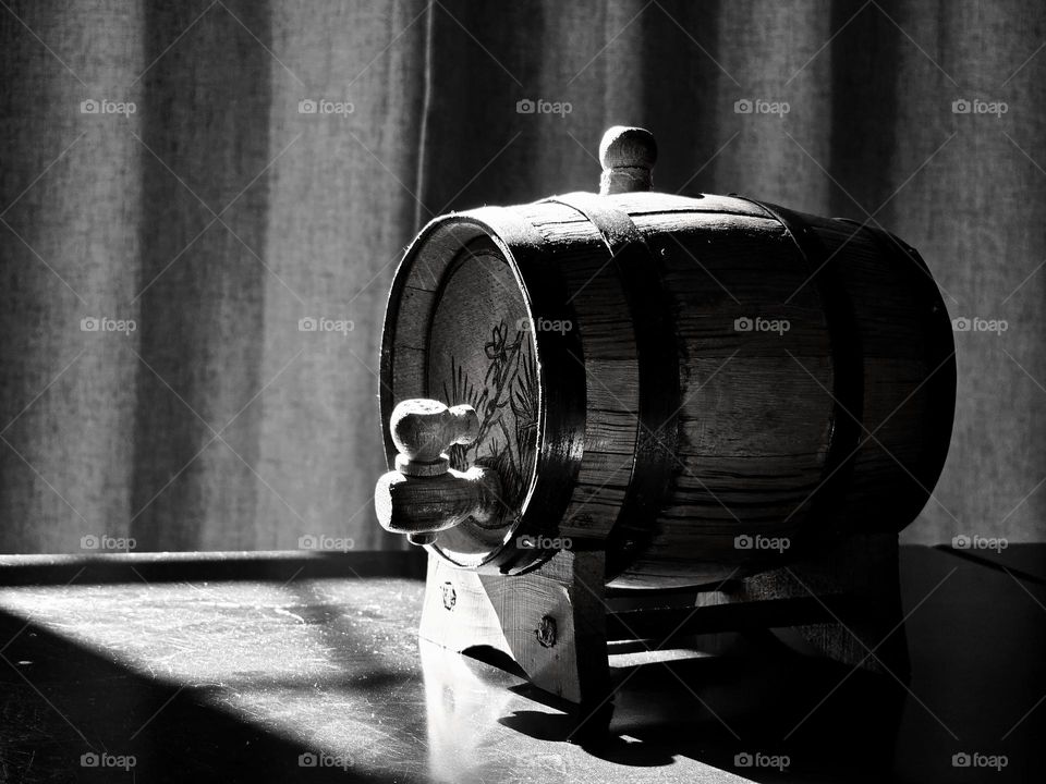 Beer barrel on a table illuminated by rays of the sun, taken on black and white style.