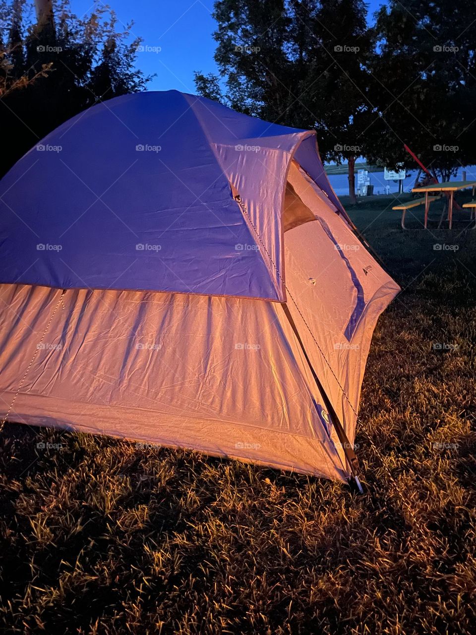 Tenting at the lake at night with warm glow of firepit lighting it up