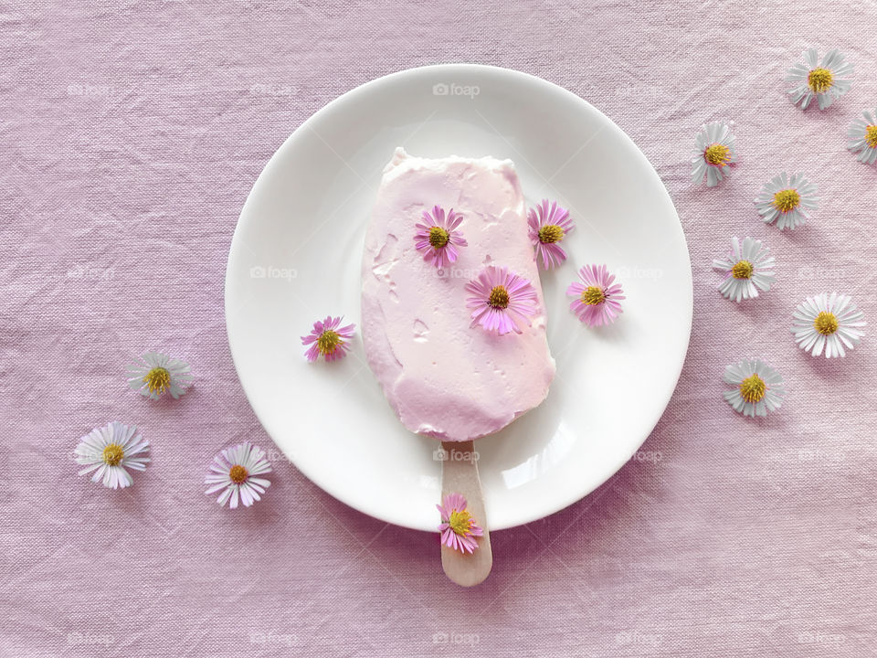 Pastel ice cream on white plate decorated with pink pastel flowers 