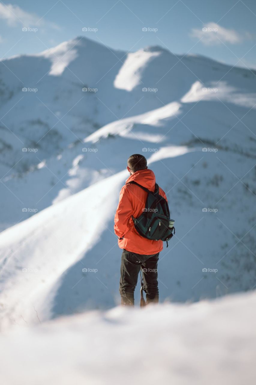 Male hiker standing on top of a snowy mountain enjoying the view.