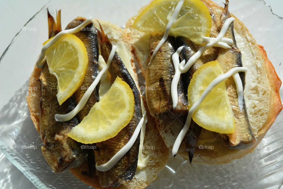 sandwiches with sprats and lemon on a plate