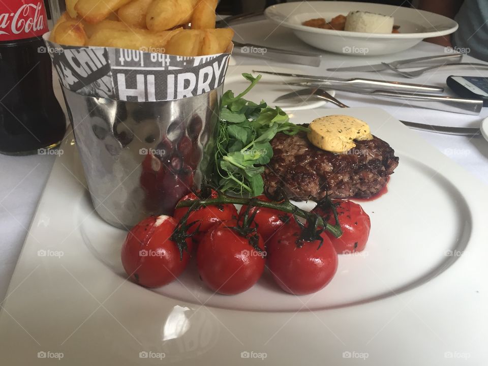 Red baked tomatoes and hamburger meet with butter on the top french fries lunch in London 