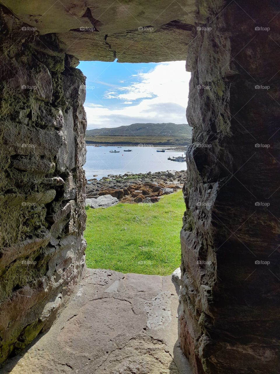 Mountains, sea, seaweed, boats, summer, view from an old church window