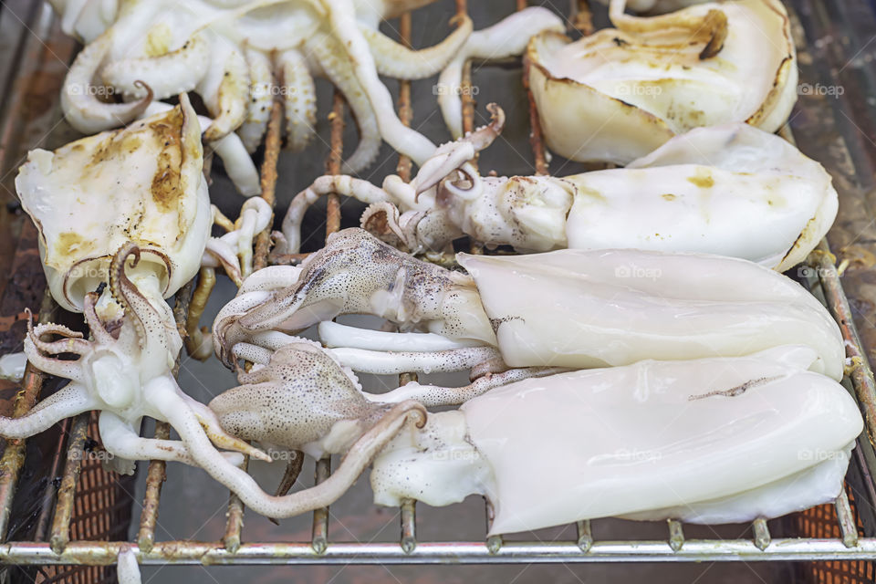 Fresh squid grilled on the steel mesh.