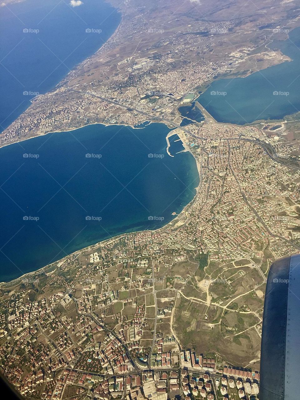 Из иллюминатора виднеется простор моря, его голубые оттенки сменяются оттенками зелени и бирюзы у берега 