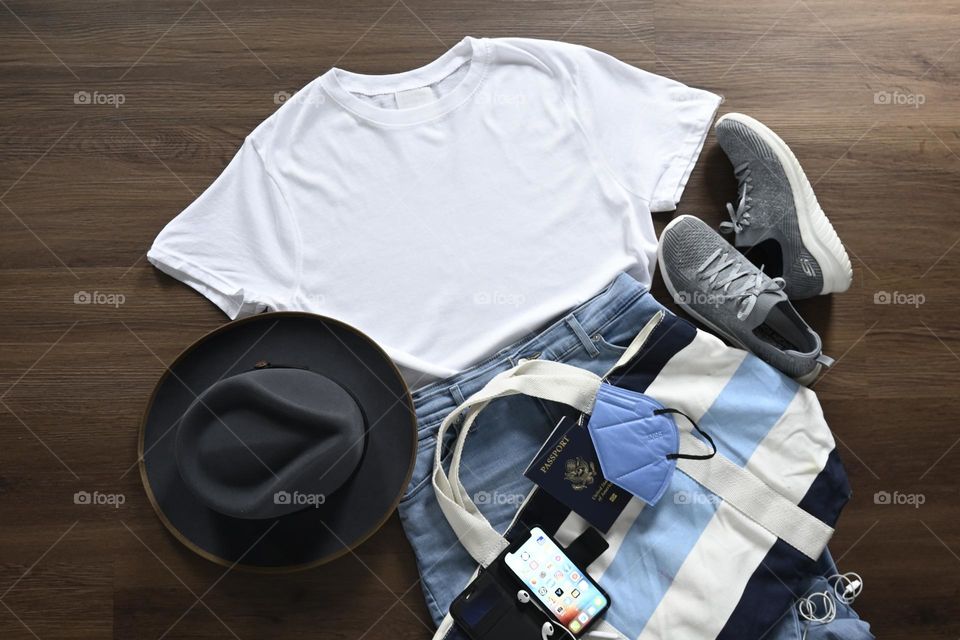 Closing essentials for travel, comfortable shirt, blue jeans, walking shoes, travel bag, iPhone lay flat