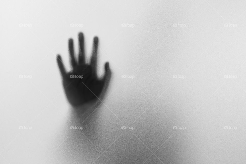 Shadow hands of the Man behind frosted glass.Blurry hand abstraction.Halloween background.Black and white picture