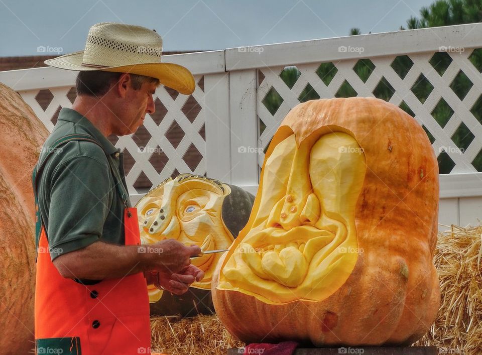 Master Pumpkin Carver. Artisan Carving A Face Into A Giant Pumpkin
