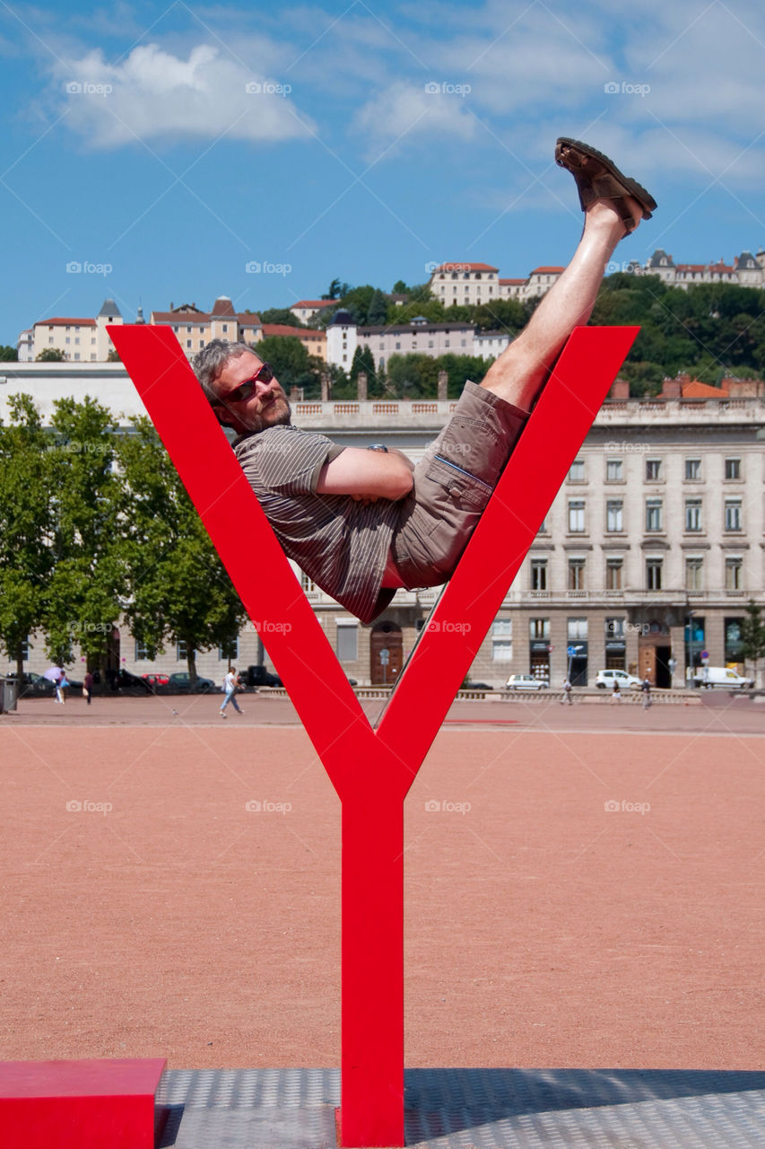 Man reclines in the Y on the only Lyon sculpture in Lyon France